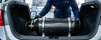 A professional mechanic inspecting a car trunk during a safe CNG vehicle conversion process.