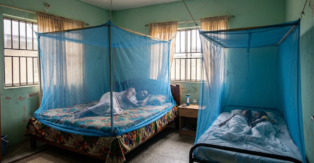 A room featuring properly installed Insecticide-Treated Nets (ITNs) suspended over sleeping areas for malaria prevention.