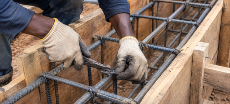  A construction worker tying steel bars, illustrating the minimum and maximum reinforcement limits in a concrete beam.
